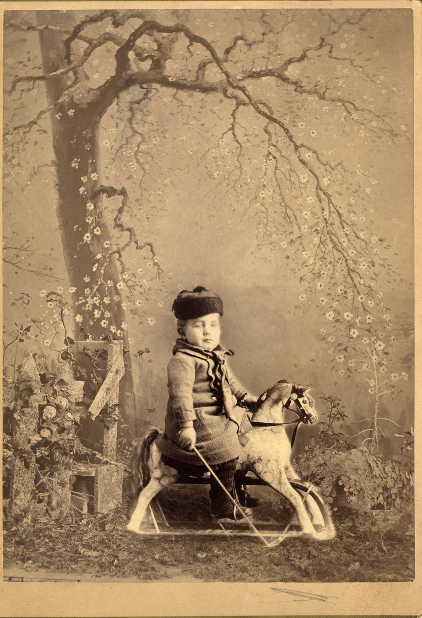 Jeune garçon assis sur un cheval à bascule avec un grand décor peint, années 1880 (photo albuminée) - American Photographer
