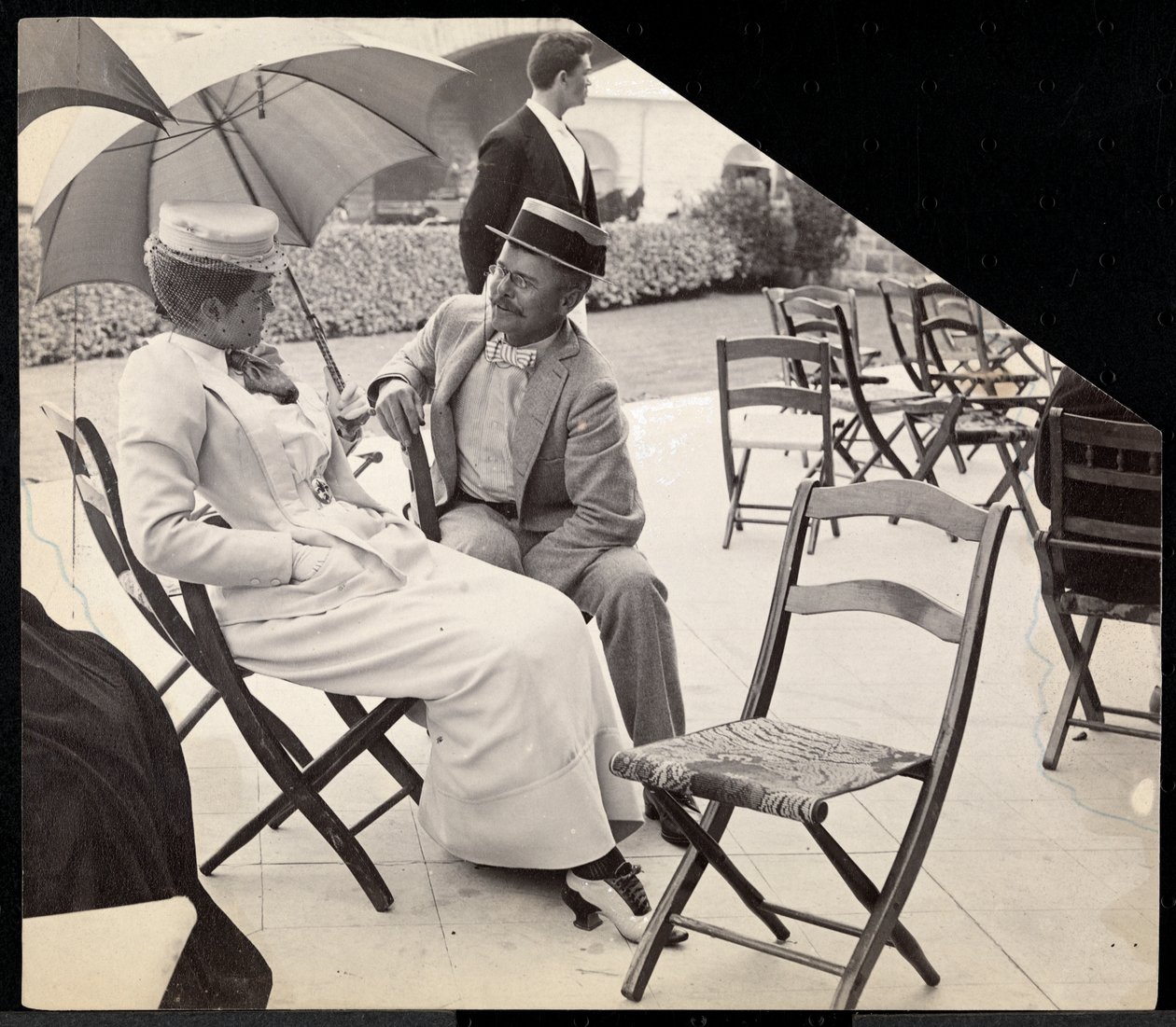 Homme et femme assis dehors sur des chaises pliantes avec une femme tenant un parasol, Narragansett, Rhode Island, 1891 - Byron Company