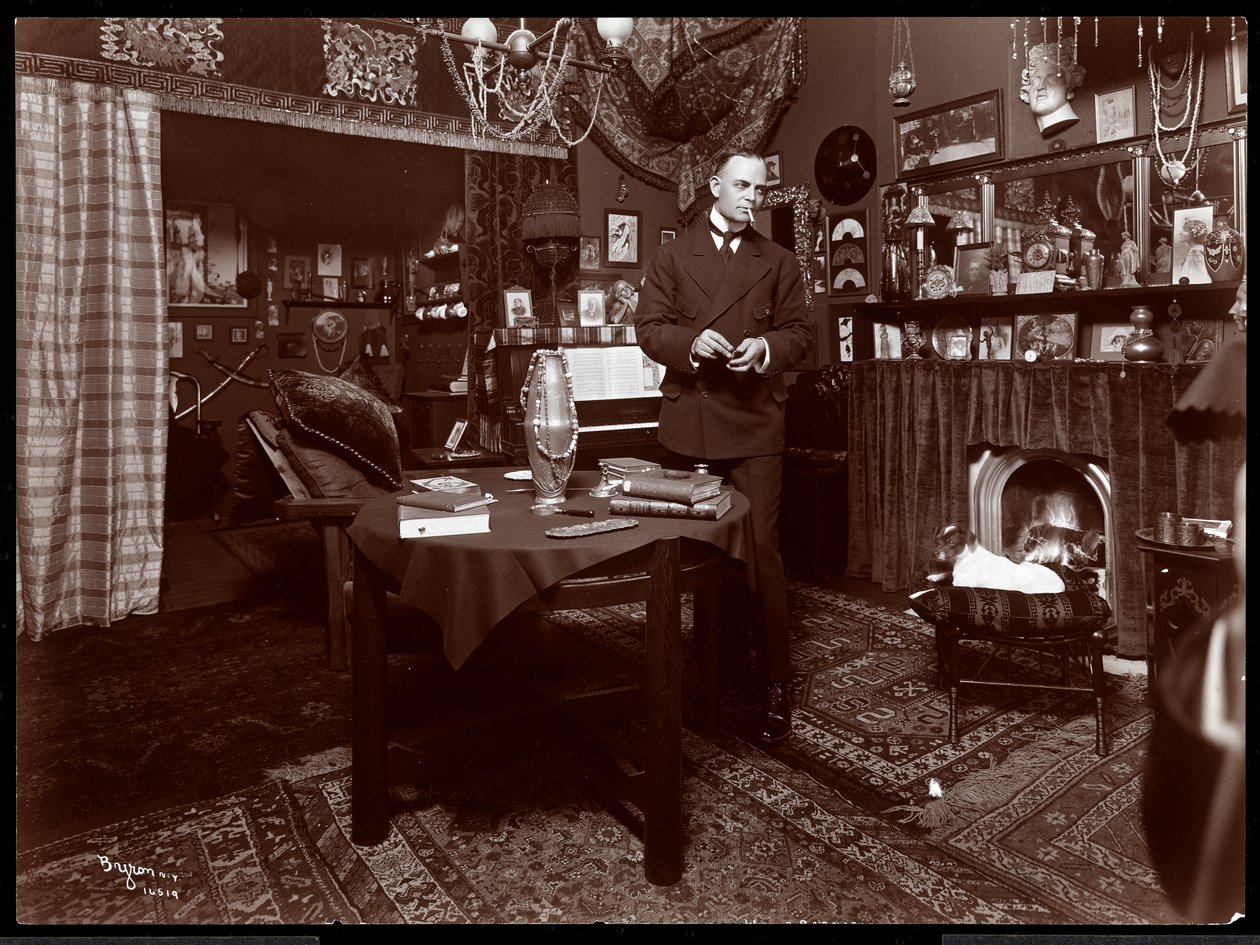 Will R. Barnes debout à une table dans son studio, 1903 - Byron Company